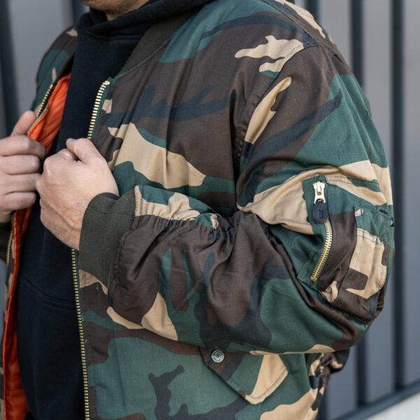 1214031 51 08 <div class="colordesc"> <big><strong>Fostex Garments® MA-1 Bomber Jack</strong></big> <hr /> <big>Bomber jas Woodland gemaakt van 65% polyester en 35% katoen.</big> <big>Voorzien van een lage kraag en 2 grote steekzakken op de voorzijde. </big> <big>De binnenvoering van de jas is oranje van kleur. Deze opvalllende kleur heeft een reden, zo konden piloten die hulp nodig hadden makkelijk gezien worden door hulptroepen. De jas is dus ook binnenstebuiten te dragen.</big> </div> <div></div> <div><strong>Twijfel je over de maat, bestel dan één maatje groter. De jas valt wat kleiner uit.</strong></div> <div><a title="Maattabel" href="https://dedump.nl/wp-content/uploads/2020/04/deDump.nl-Fostex-MA-1-Bomber-Jack-maattabel.pdf" target="_blank" rel="noopener noreferrer"><button><span style="color: #ef471f; font-size: medium;"><strong>Maattabel</strong></span></button></a></div>