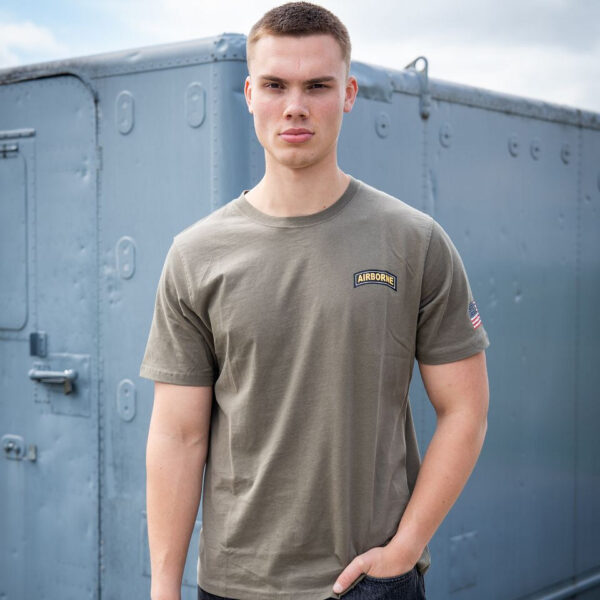 133657 11 04 Het T-shirt 101st Airborne Roundel is gemaakt van 100% BCI katoen en biedt een comfortabele en zachte draagervaring dankzij de peach finish. Met een zware kwaliteit van 170 g/m² is dit T-shirt perfect voor zowel dagelijks gebruik als outdoor activiteiten. Het is voorzien van een opvallende airborne tekstprint op de linkerborst en een grote print op de achterkant. Verkrijgbaar in een stijlvolle groene kleur, is dit T-shirt een must-have voor elke militair of outdoor liefhebber.