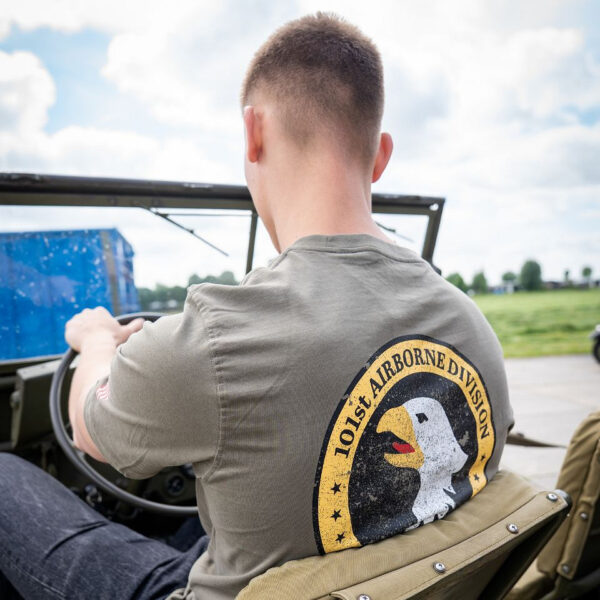 133657 11 08 Het T-shirt 101st Airborne Roundel is gemaakt van 100% BCI katoen en biedt een comfortabele en zachte draagervaring dankzij de peach finish. Met een zware kwaliteit van 170 g/m² is dit T-shirt perfect voor zowel dagelijks gebruik als outdoor activiteiten. Het is voorzien van een opvallende airborne tekstprint op de linkerborst en een grote print op de achterkant. Verkrijgbaar in een stijlvolle groene kleur, is dit T-shirt een must-have voor elke militair of outdoor liefhebber.