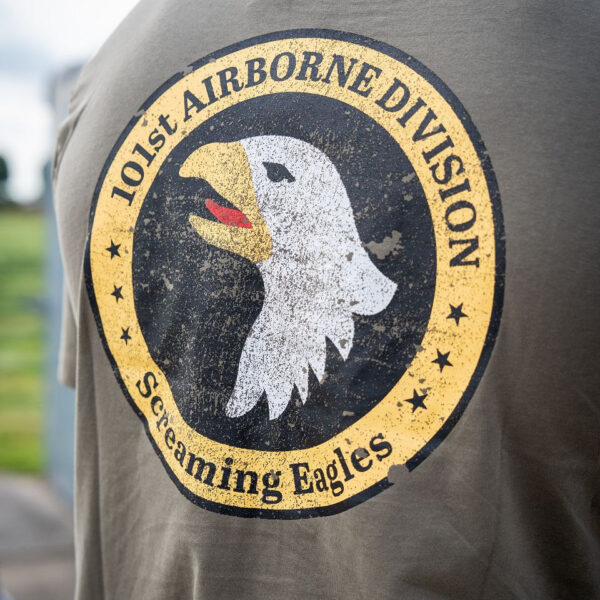133657 11 10 Het T-shirt 101st Airborne Roundel is gemaakt van 100% BCI katoen en biedt een comfortabele en zachte draagervaring dankzij de peach finish. Met een zware kwaliteit van 170 g/m² is dit T-shirt perfect voor zowel dagelijks gebruik als outdoor activiteiten. Het is voorzien van een opvallende airborne tekstprint op de linkerborst en een grote print op de achterkant. Verkrijgbaar in een stijlvolle groene kleur, is dit T-shirt een must-have voor elke militair of outdoor liefhebber.