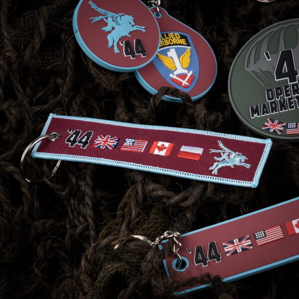 251306 11029 99 02 <p>Ontdek de Sleutelhanger Market Garden '44 #171, een prachtig vervaardigd accessoire van 100% fijngeweven stof. Deze sleutelhanger, met gedetailleerde logo's van de Market Garden Pegasus en de bijbehorende vlaggen aan beide zijden, herdenkt de moedige operatie uit september 1944. Een must-have voor iedereen die de geschiedenis van de Tweede Wereldoorlog waardeert en de helden van Operatie Market Garden wil eren.</p>